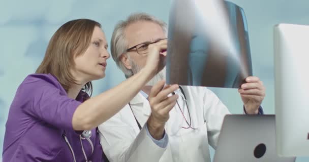 Médico y una enfermera mirando rayos X y tomografías computarizadas en el hospital. Tiro medio, 4k en cámara lenta . — Vídeo de stock