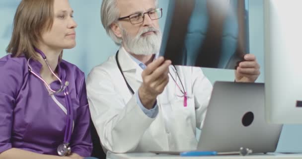Лікар і медсестра, які дивляться на рентгенівські та клітинні сканування в лікарні. Середній постріл, повільний рух 4k . — стокове відео