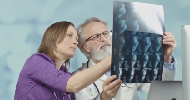 Врач и медсестра смотрят на рентген и КТ в больнице. Medium shot, 4k slow motion . — стоковое видео