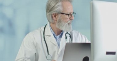 Ofisindeki ortopedik doktor romatizmalı hastanın röntgen ve tomografi sonuçlarına bakıyor.. 