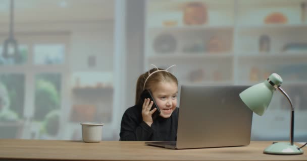 Vijf jaar oud meisje typt op de computer achter het bureau in een gezellige woonkamer. slow motion 4K. — Stockvideo