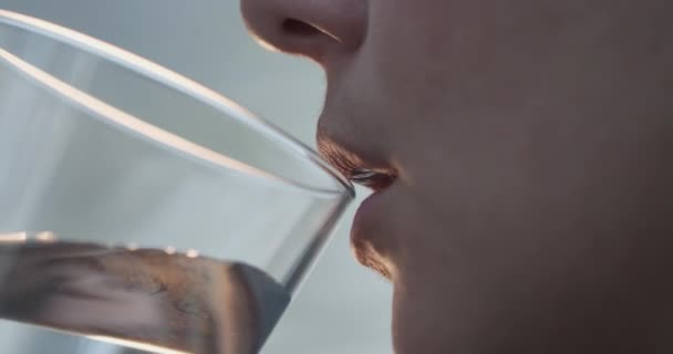Жіночі губи п'ють воду з прозорого скла. 4k повільний рух — стокове відео