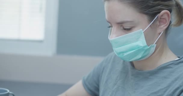 Jonge blanke vrouw werken vanuit huis met een masker, tijdens verblijf thuis corona tijden — Stockvideo