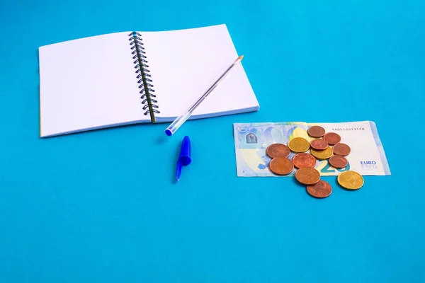 set of banknote, coins and notebook on blue background