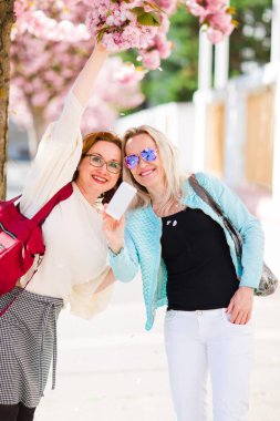 Kiraz çiçeğinin altında poz veren iki kadın