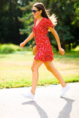 Parkta koşan kırmızı elbiseli genç kadın.