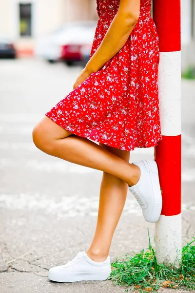 Szczegóły dotyczące nóg młodej kobiety przebywającej przy czerwono-białych kolumnach — Zdjęcie stockowe