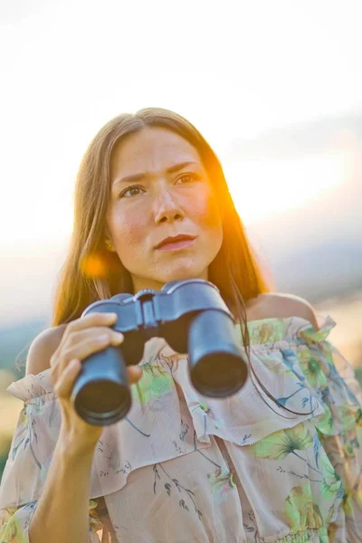 Woman in summer dress holding binoculars