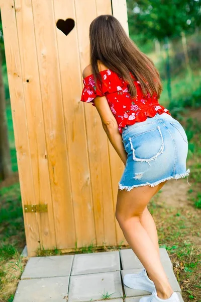 Una chica en falda de jeans cortos esperando por madera trabajada Fotos de stock