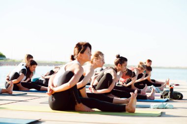 Gölün yakınındaki bir pontonda yoga derslerine katılan büyük bir grup insan..