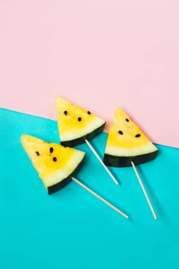 Pembe-mavi arka planda olgun sarı karpuz dilimlerini kes.