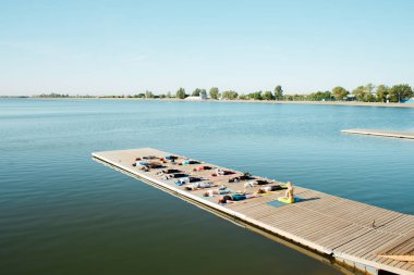 Sabah bir grup insan göl kenarındaki iskelede yoga yapıyor.
