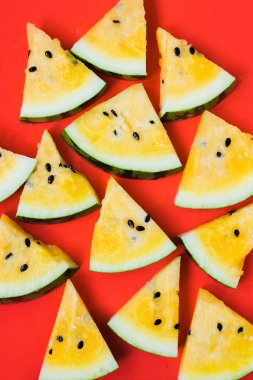 Kırmızı zemin üzerinde olgun sarı karpuz dilimlerini kes.