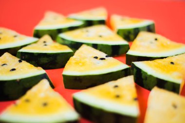 Kırmızı zemin üzerinde olgun sarı karpuz dilimlerini kes.