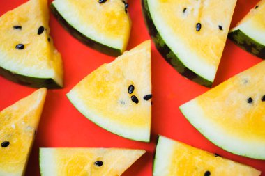 Kırmızı zemin üzerinde olgun sarı karpuz dilimlerini kes.