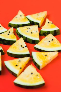 Kırmızı zemin üzerinde olgun sarı karpuz dilimlerini kes.