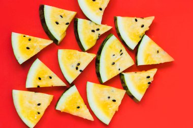 Kırmızı zemin üzerinde olgun sarı karpuz dilimlerini kes.