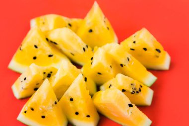 Kırmızı zemin üzerinde olgun sarı karpuz dilimlerini kes.