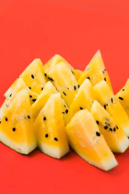Kırmızı zemin üzerinde olgun sarı karpuz dilimlerini kes.