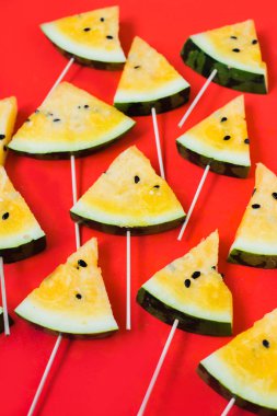 Kırmızı zemin üzerinde olgun sarı karpuz dilimlerini kes.