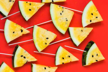 Kırmızı zemin üzerinde olgun sarı karpuz dilimlerini kes.