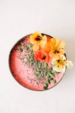 Hindistan cevizi tabağında sağlıklı vejetaryen kahvaltısı. İçinde nasturtiyum çiçekleri, çim tohumları ve kabak tohumları var.