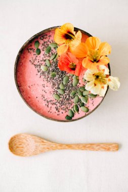 Hindistan cevizi ve bambu kaşığı içinde kahvaltı. İçinde nasturtiyum çiçekleri, çim tohumları ve kabak tohumları var.