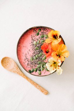 Hindistan cevizi ve bambu kaşığı içinde kahvaltı. İçinde nasturtiyum çiçekleri, çim tohumları ve kabak tohumları var.