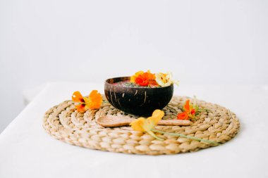 Hindistancevizi tabağında sağlıklı bir kahvaltı ve doğal hasır peçetede nasturtiyum çiçekli bambu kaşığı.