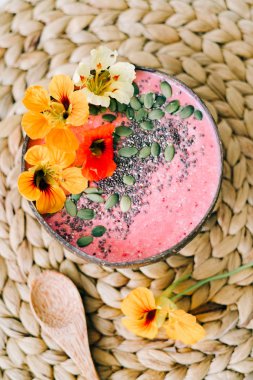 Hindistancevizi tabağında sağlıklı bir kahvaltı ve doğal hasır peçetede nasturtiyum çiçekli bambu kaşığı.