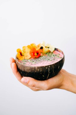 Bir tabak hindistan cevizli sağlıklı kahvaltı. Elinde de nasturtiyum çiçekleri var.