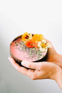 Bir tabak hindistan cevizli sağlıklı kahvaltı. Beyaz arka planda da nasturtiyum çiçekleri var.