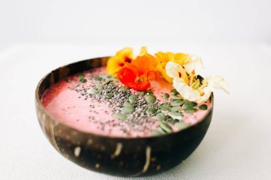 Hindistan cevizi tabağında sağlıklı vejetaryen kahvaltısı. İçinde nasturtiyum çiçekleri, çim tohumları ve kabak tohumları var.