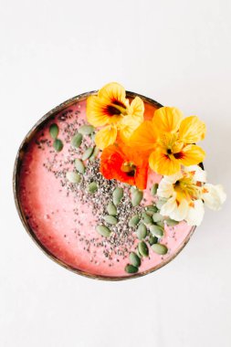 Hindistan cevizi tabağında sağlıklı vejetaryen kahvaltısı. İçinde nasturtiyum çiçekleri, çim tohumları ve kabak tohumları var.