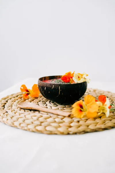 Zdrowe śniadanie w talerzu kokosa i łyżki bambusa z nasturcji kwiaty na naturalnej wiklinowej serwetce — Zdjęcie stockowe