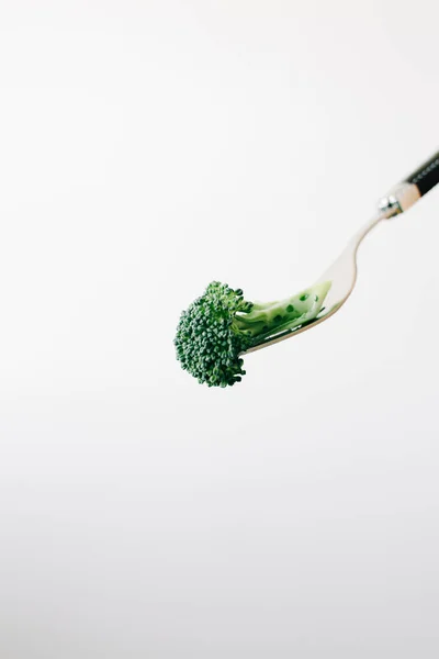 Un tenedor con una inflorescencia verde de brócoli fresco sobre un fondo blanco. comida vegana — Foto de Stock