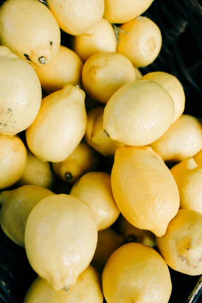 Limões amarelos maduros encontram-se em uma cesta de vime no mercado orgânico — Fotografia de Stock