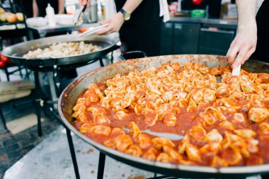 Domates soslu ızgara ravioli büyük bir tava sokak yemeğinin içinde pişirilir.