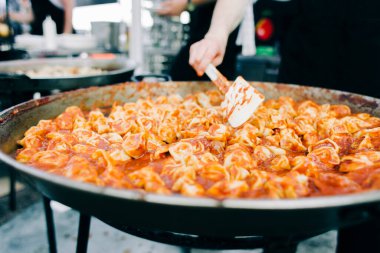 Domates soslu ızgara ravioli büyük bir tava sokak yemeğinin içinde pişirilir.