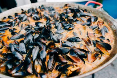 Lezzetli istiridyeler bir markette kremalı domates sosunda büyük bir kızartma tavasında pişiriliyor.