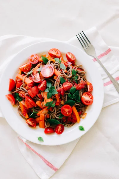 Finom olasz tészta paradicsommal, sárgarépával és bazsalikommal fehér szalvétára — Stock Fotó