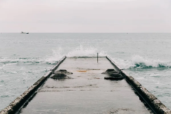 Deniz dalgaları yıkılmış rıhtıma çarpıyor. Güzel doğal manzara — Stok fotoğraf