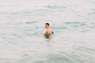 a young guy is swimming in the blue clear water of the ocean