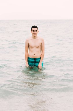 a young guy is swimming in the blue clear water of the ocean