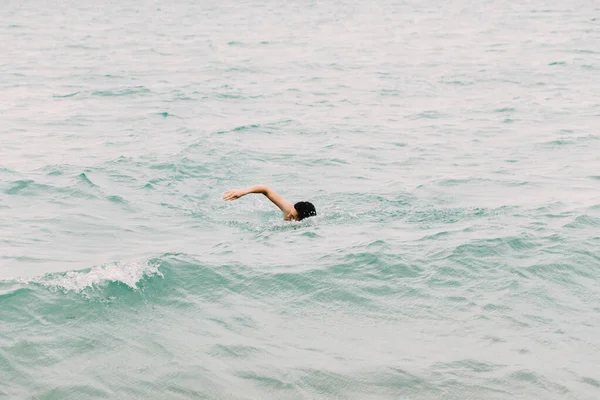 Un joven está nadando en las azules aguas cristalinas del océano — Foto de Stock