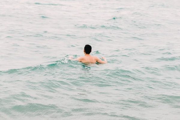 Молодий хлопець плаває у блакитній прозорій воді океану — стокове фото