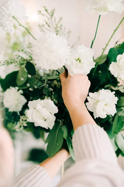 A virágos összegyűjti a virágos elrendezése finom rózsa virágok és friss növényzet a tervezés az esküvői asztal a fehér teremben — Stock Fotó