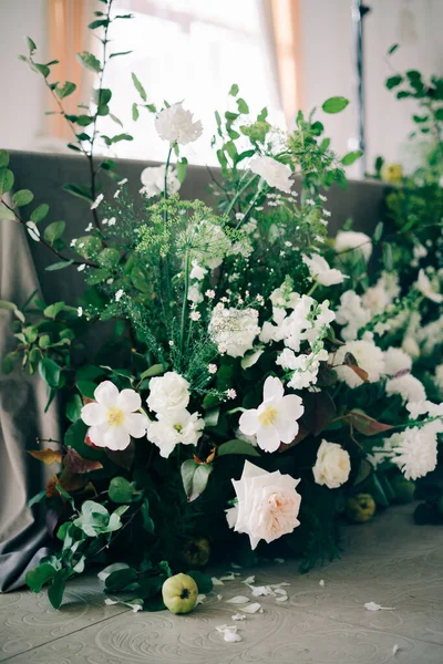 Virágos elrendezése fehér finom virágok és friss növényzet a tervezés az esküvői asztal a menyasszony és a vőlegény a fehér teremben — Stock Fotó