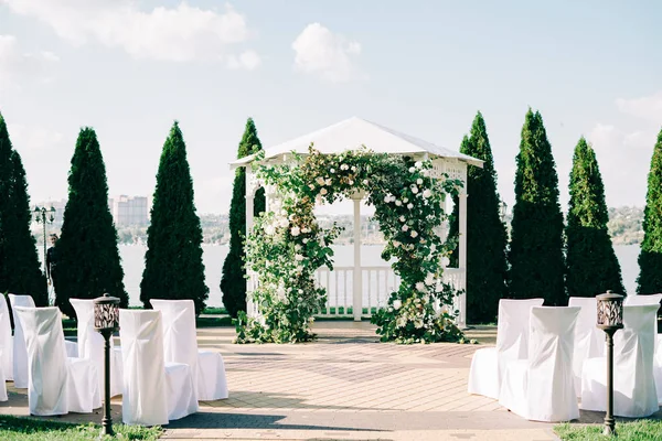 Wedding arch decorated with a beautiful floral arrangement of white flowers and fresh branches of greenery on a Sunny day — Stock Photo, Image