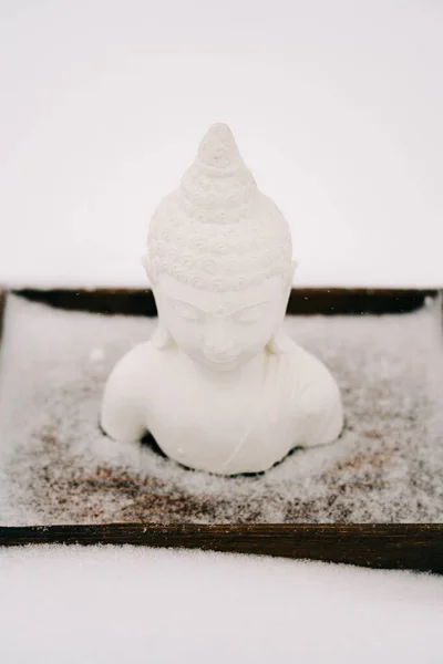 Biała Figurka Buddy Wykonana Gipsu Drewnianej Podstawce Podczas Opadów Śniegu — Zdjęcie stockowe